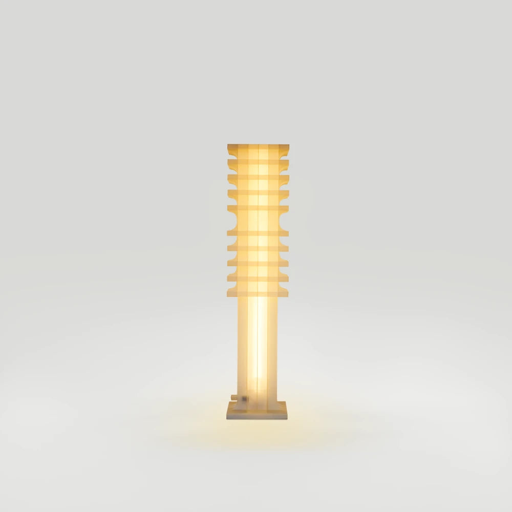 Front view of the illuminated Citadel Short Floor Light by Ultramar Studio, featuring a translucent column, layered upper section and square base.